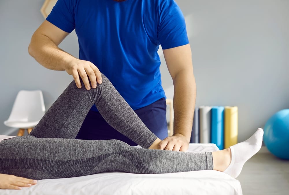 Chiropractor guiding a patient through lower body and hip mobility techniques to reduce pain and restore functional movement – Juneau Pain Center