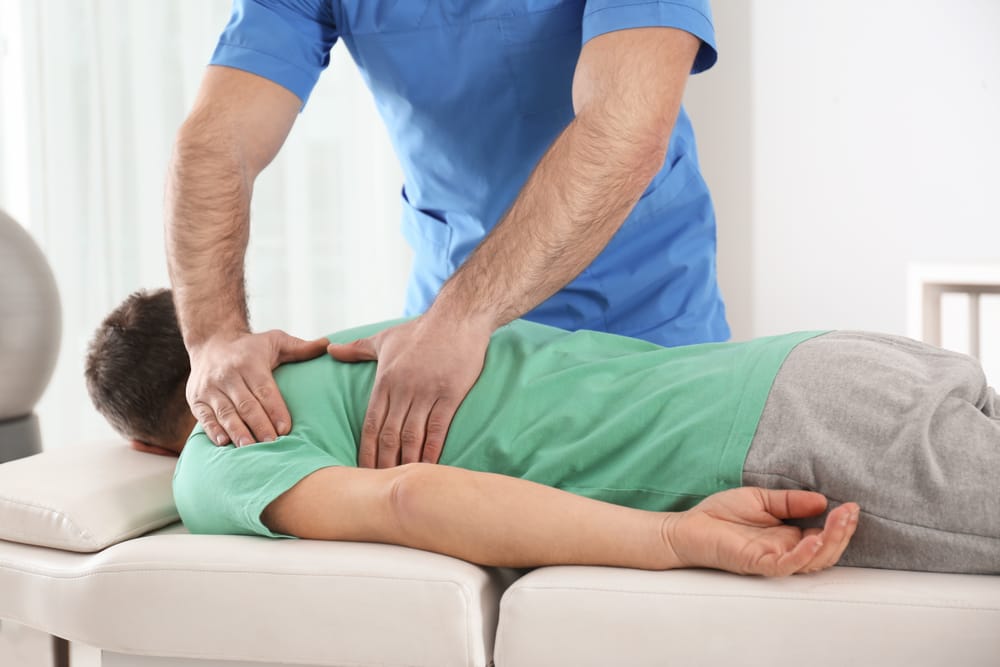 Chiropractor performing a gentle spinal adjustment to relieve back pain, improve alignment, and support long-term musculoskeletal health – Juneau Pain Center